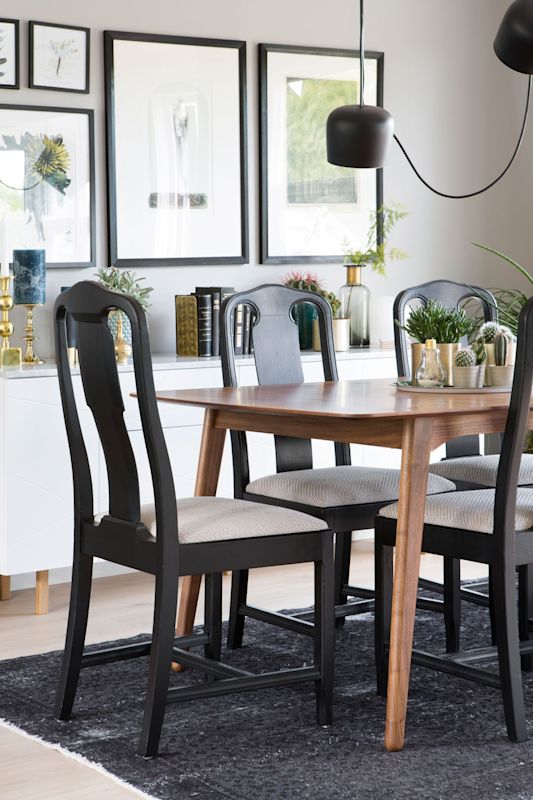 Moderne spisestue med trebord, svarte stoler, sort teppe, hvit skjenk med grønne planter