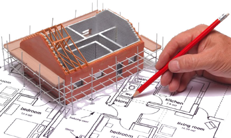 Oransje murhusmodell under bygging med grå stillas på plantegning, hånd med rød blyant
