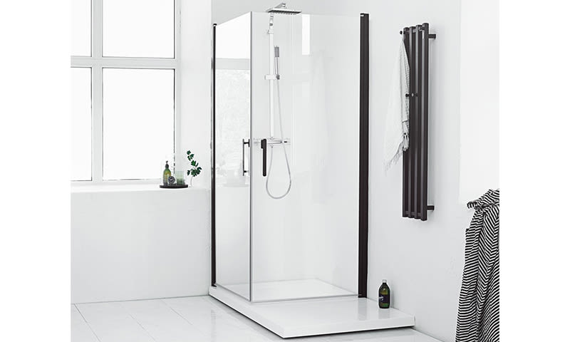 Hvitt minimalistisk baderom med glassdusj i sort ramme, stort vindu, svart håndkletørker og flasker.