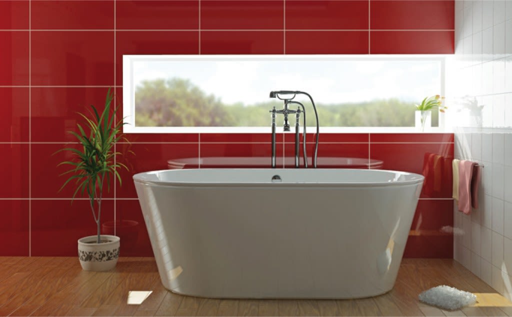 Hvit frittstående badekar foran smalt vindu med grønt utsyn, røde veggfliser og plante