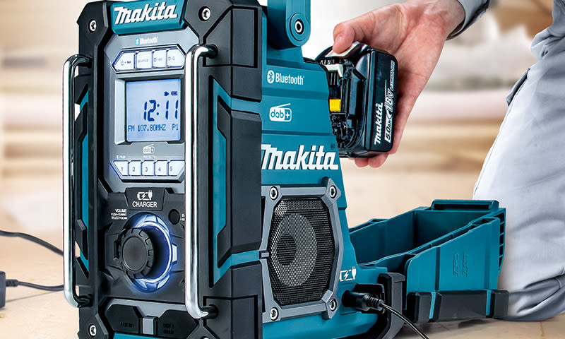 Turkis Makita Bluetooth-radio med DAB+-skjerm og hånd som setter inn 18 V batteri