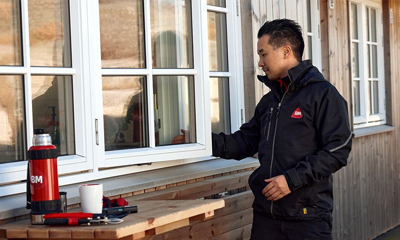 Mann utenfor bygning som ser på et hvitt vindu