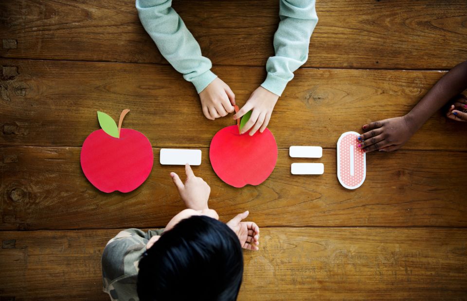 Kids using paper apple cut outs to learn math