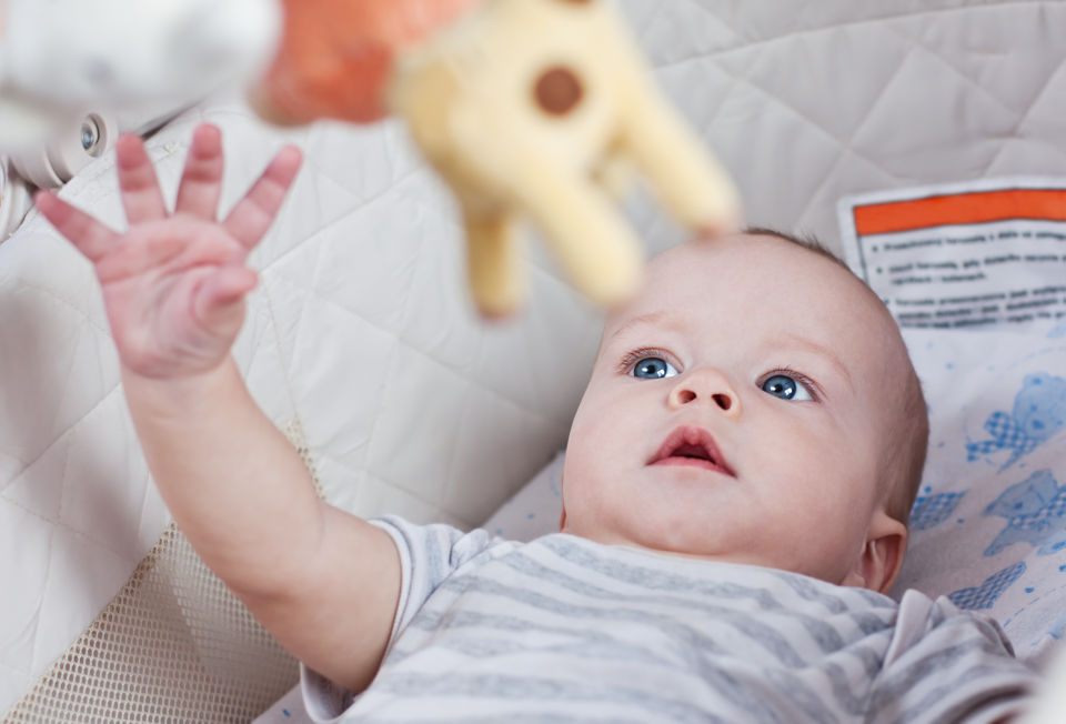 Baby Boy in crib Reaching for Toy