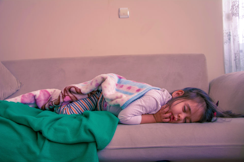 Girl sleeping on couch with green blanket