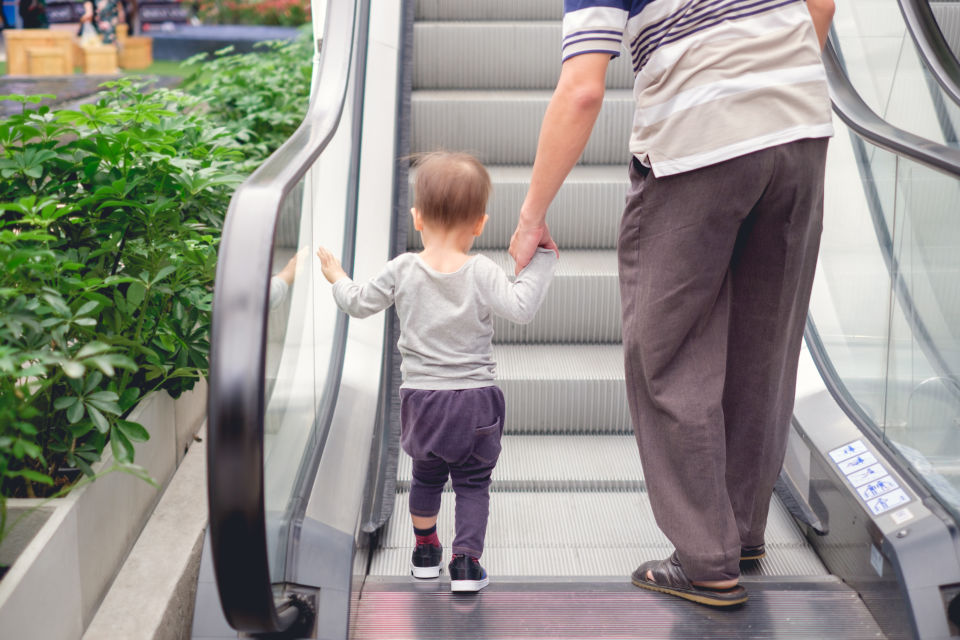 Father Holding boys handing before riding escalator