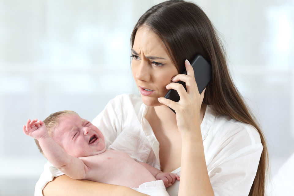 Madre preocupada llamando por teléfono, su bebé llora