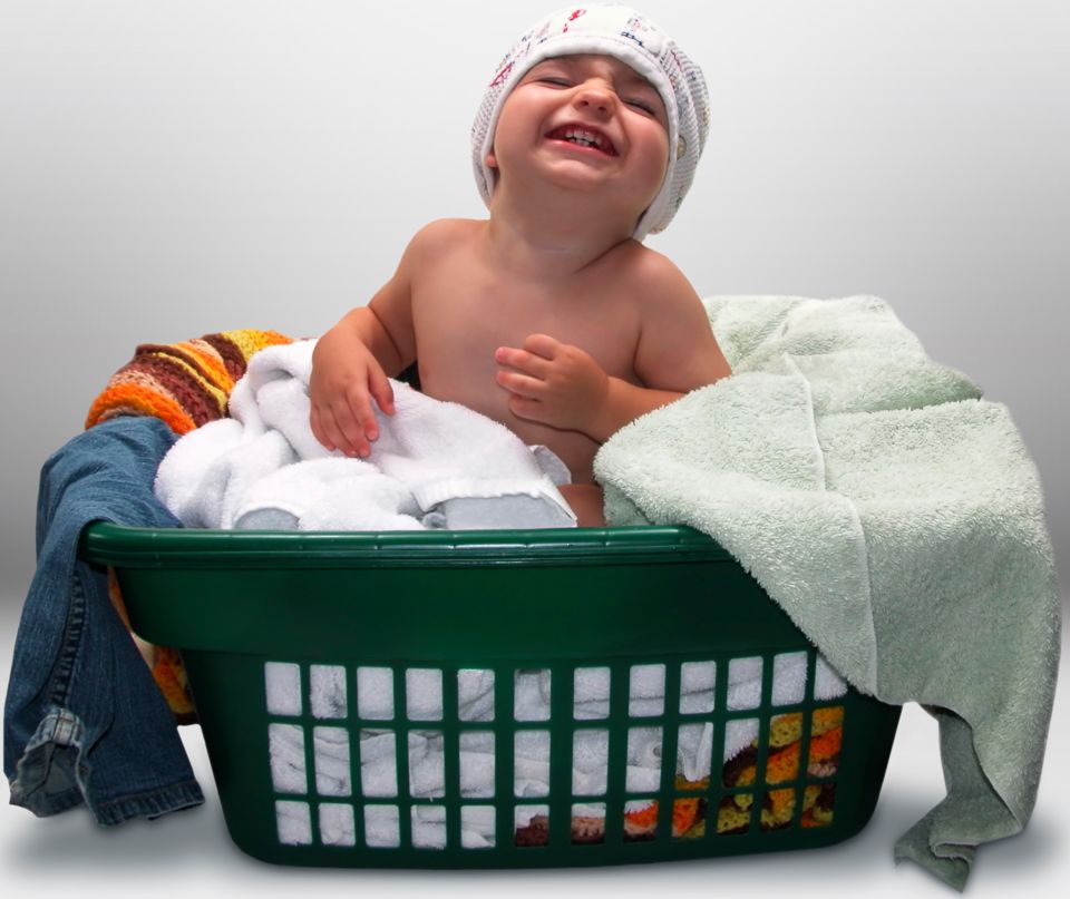 Boy in clothing basket smiling at camera 