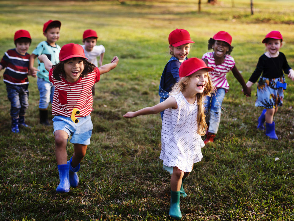 Kids wearing red hats running on grass