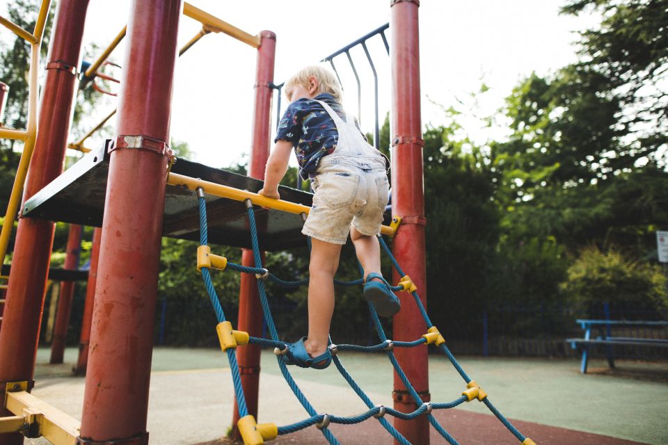 Boy in overalls Climbing up a playground structure