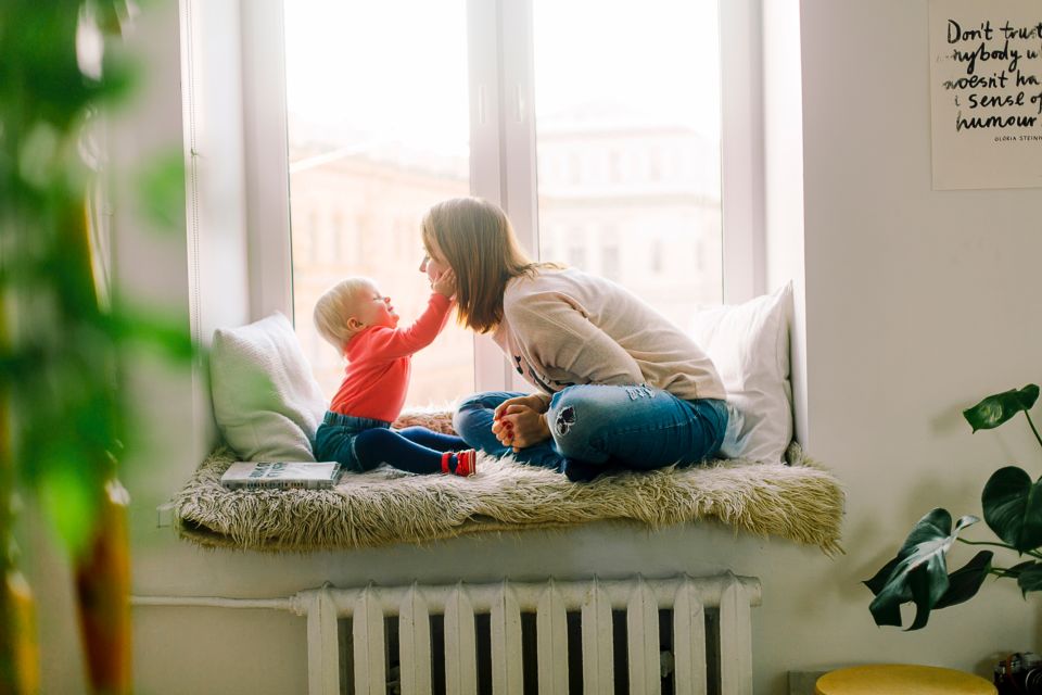 Baby and mother sitting, daughter reaching for mothers cheeks