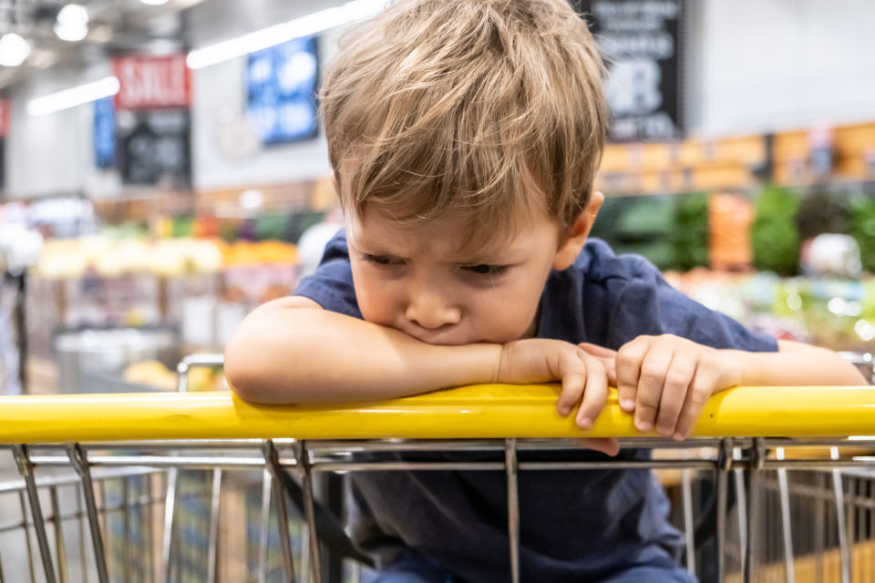 Bebé sentado en el suelo llorando – Niño angustiado sentado en un carrito de supermercado