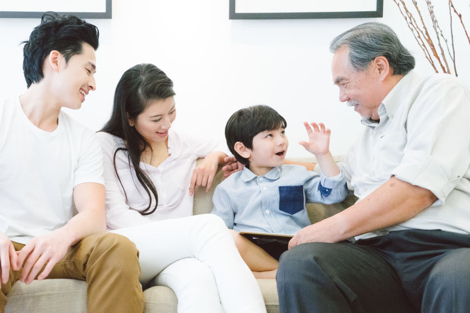 Young Parents and boy spending time with grandpa on couch