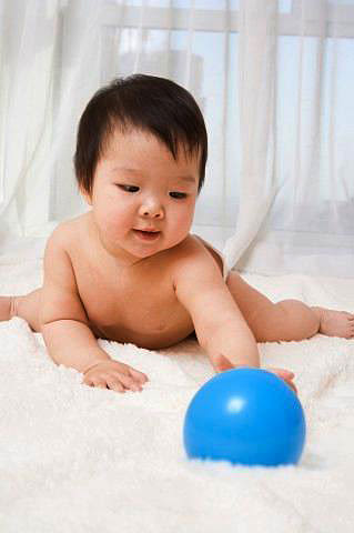Baby laying down reaching for blue ball