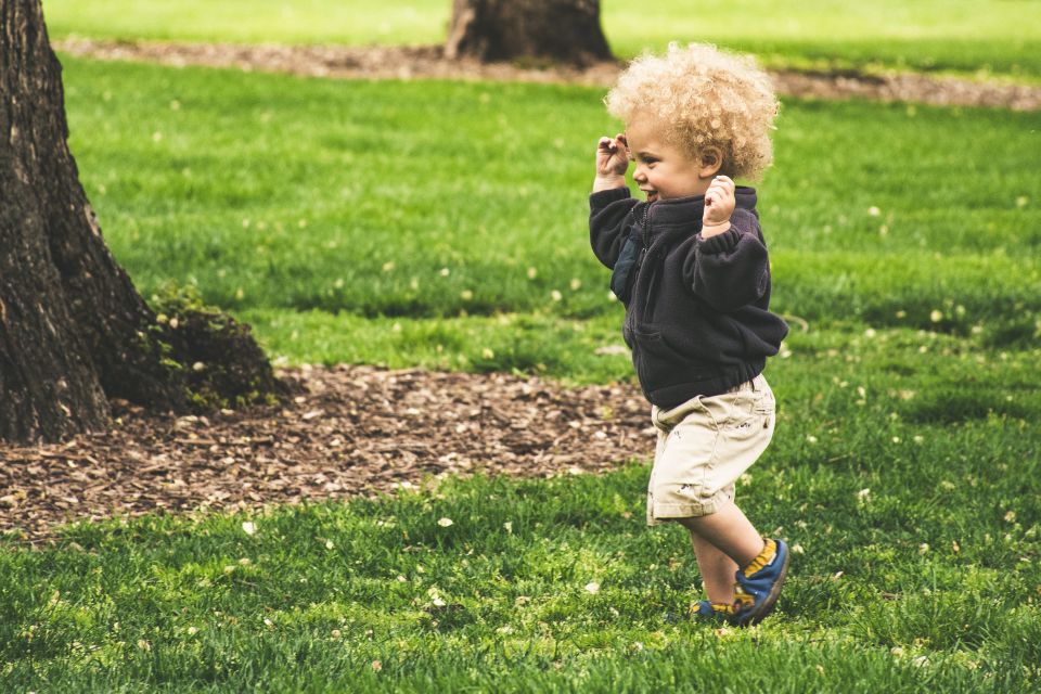 Boy with curly blonde hair running at park
