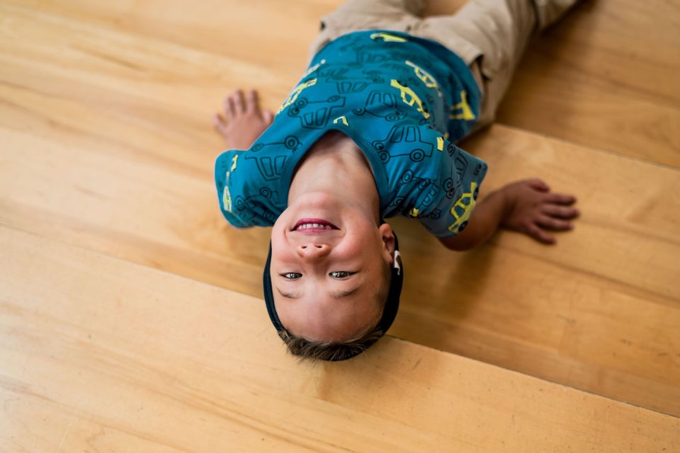 Boy laying on floor smiling at camera upside down