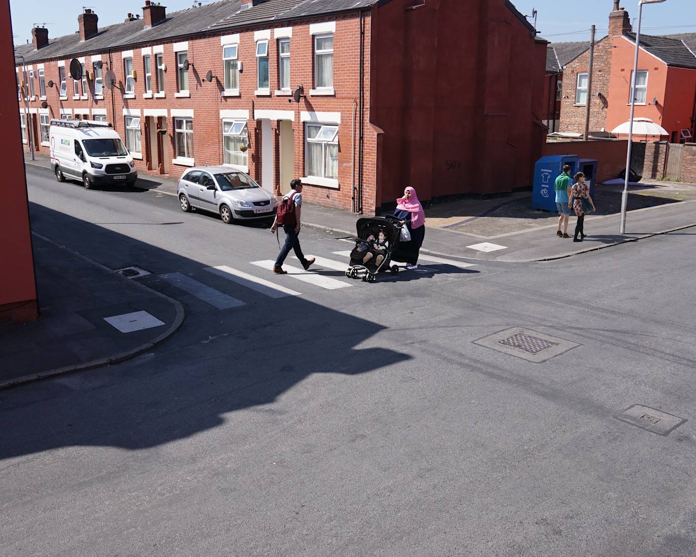 A side road zebra with people crossing the road