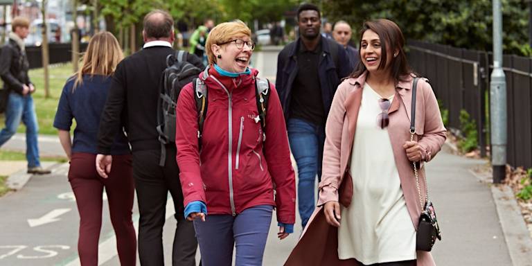Two women walking in central Manchester, laughing and chatting