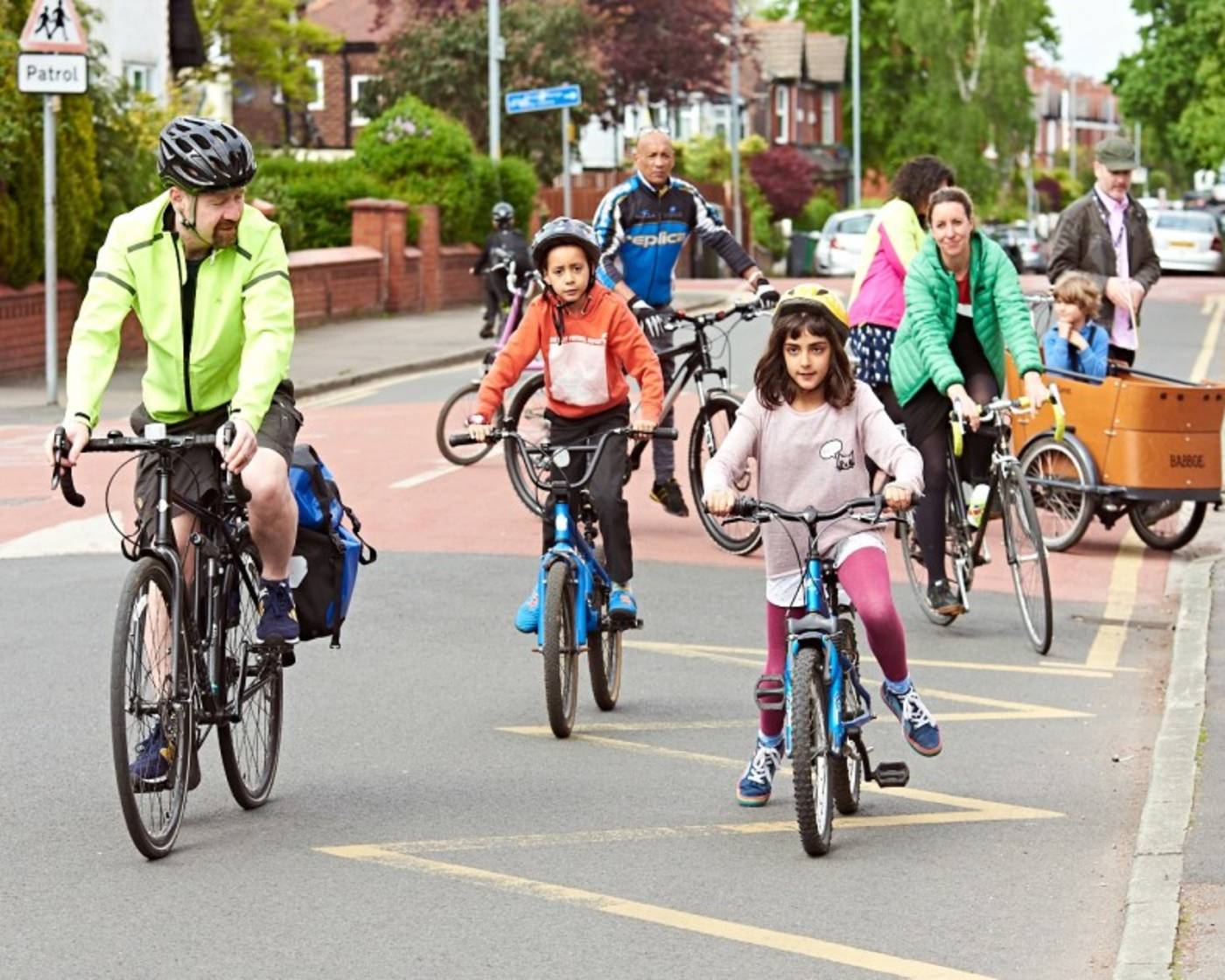 Group of men, women and children cycling outside a school