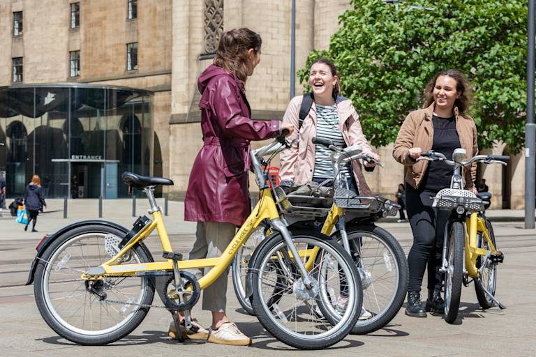 Three friends stood with cycle hire bikes having a conversation