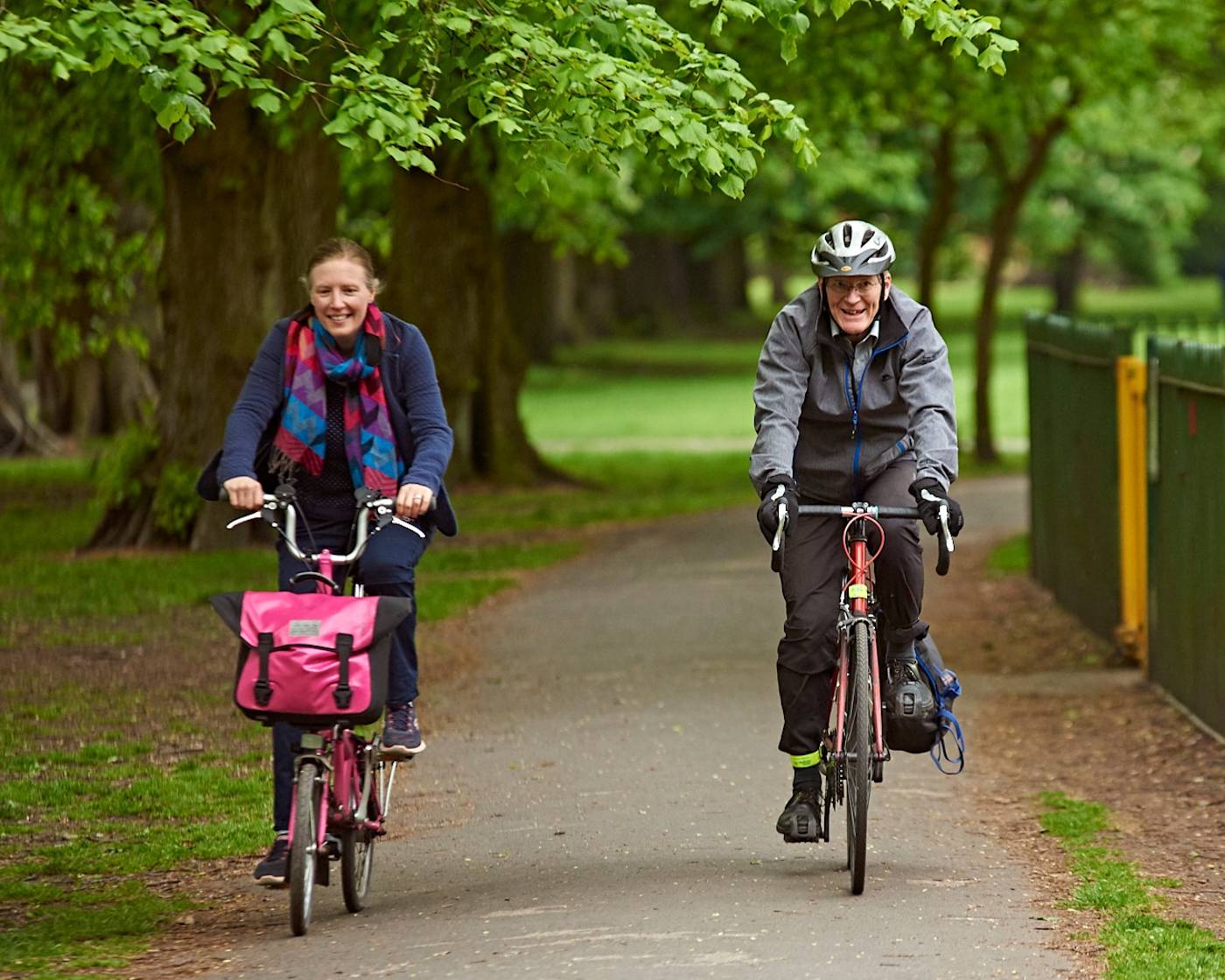 Man and woman cycling side by side in a park