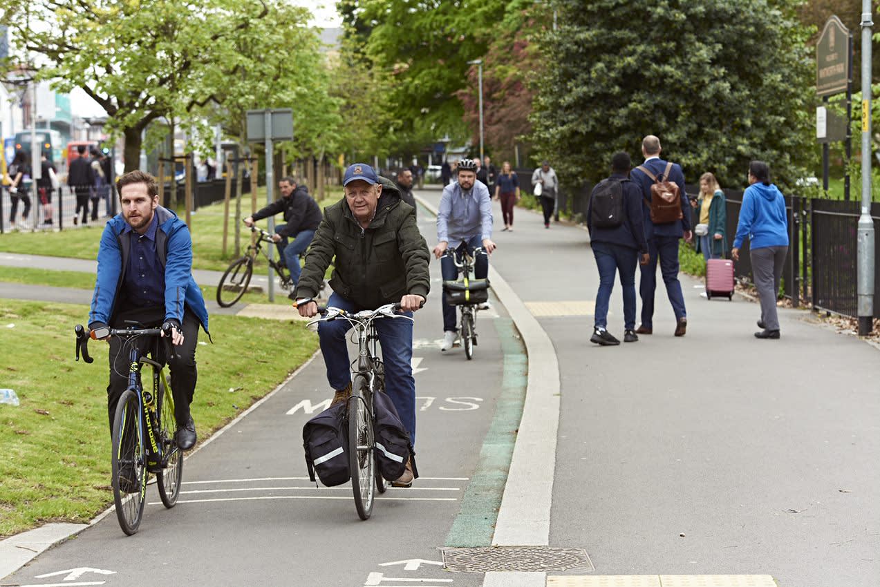 An image of a street with multiple people cycling in the cycle lane