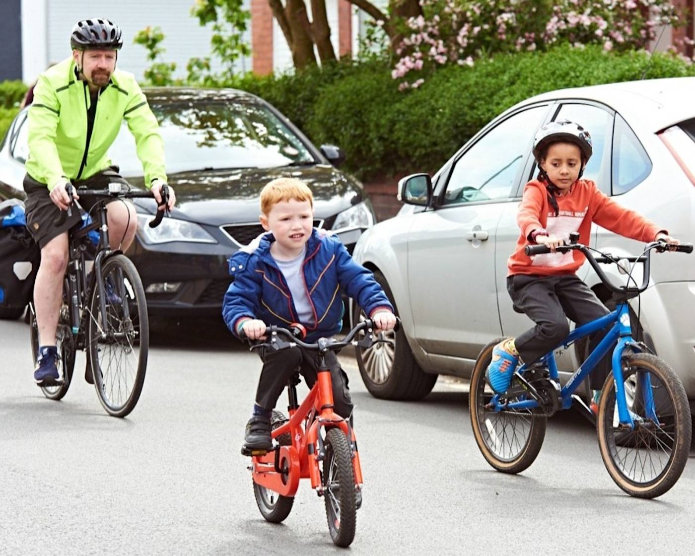 A child cycling to school with parents down a quiet road