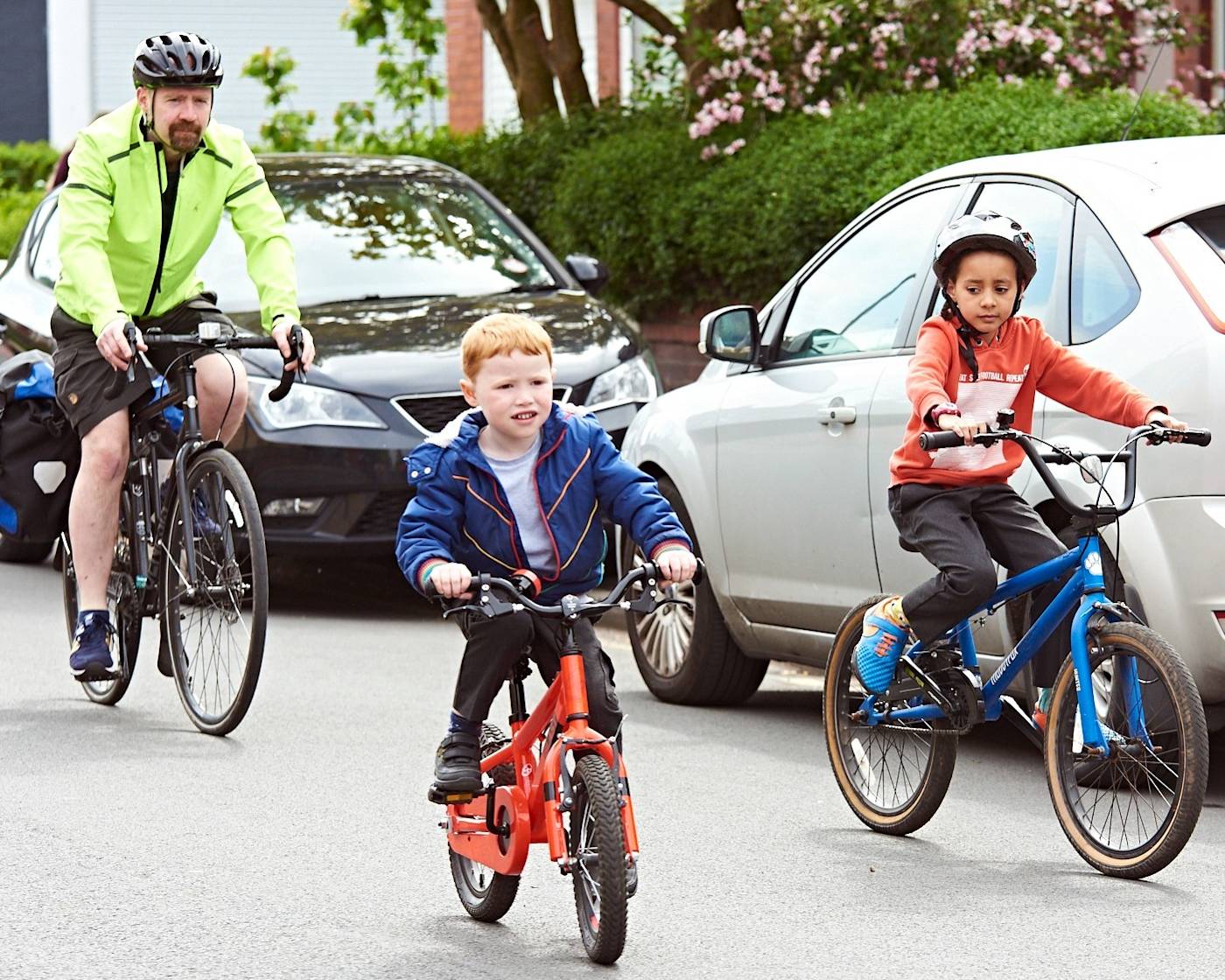 A child cycling to school with parents down a quiet road