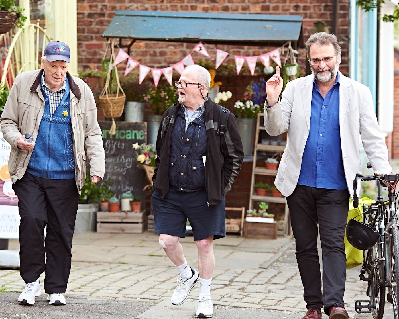 Three older men walking and laughing