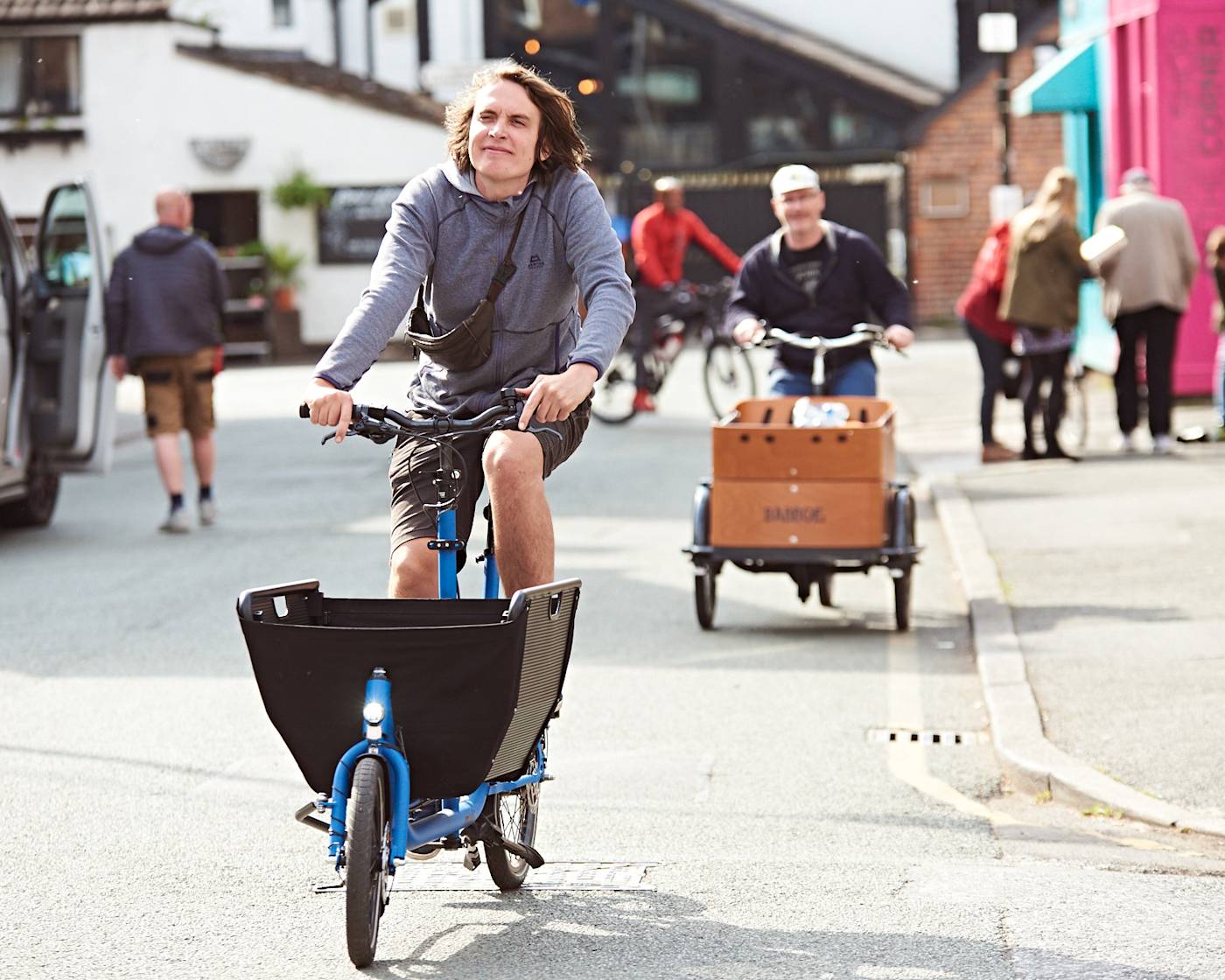 Two people riding cargo bikes along a street