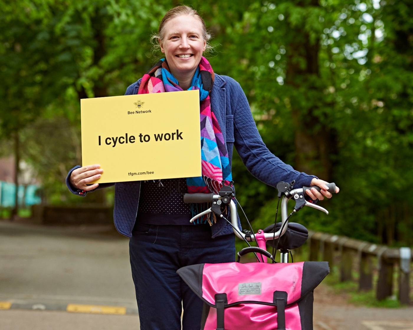Image of woman with a bike holding a card saying 'I cycle to work'