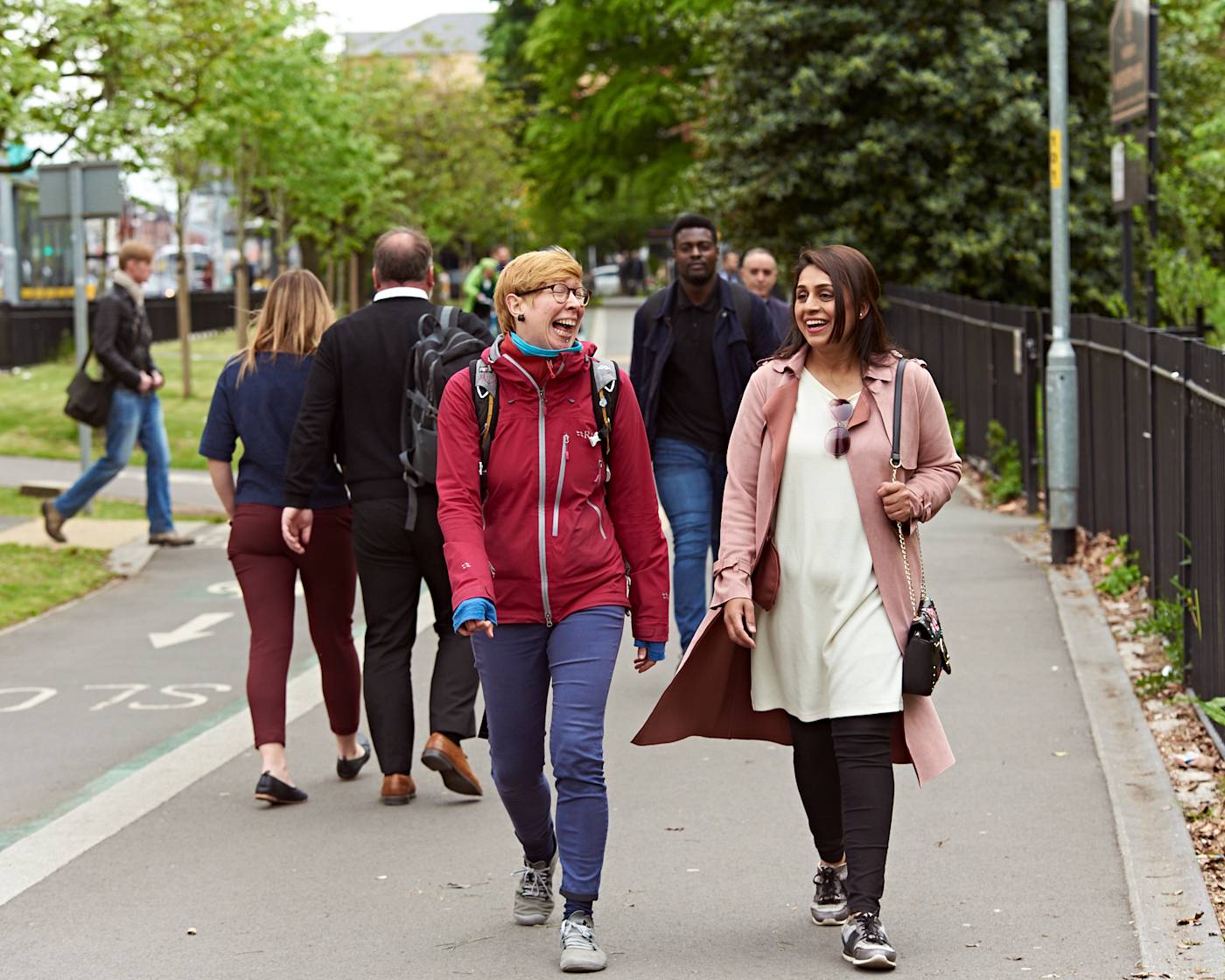 Two women laughing as they walk through a park