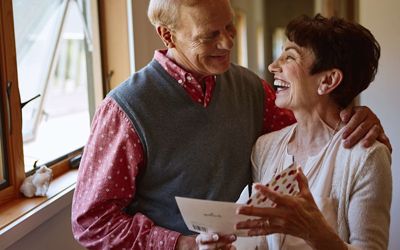 Two older people smiling over a card ARTICLE HERO IMAGE