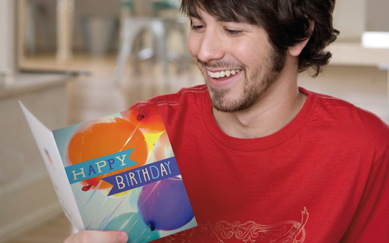 L male red shirt smiling at birthday card