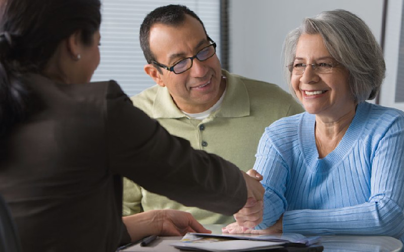 L couple smiling females shaking hands across table