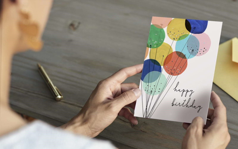 Happy Birthday Card over Woman's Shoulder ARTICLE HERO IMAGE