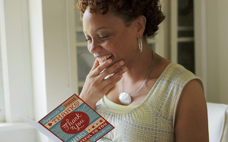 L female reading thank you card and laughing