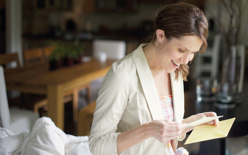 L female with surprised expression reading greeting card