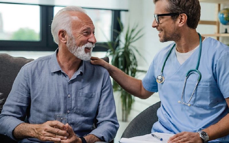 L doctor nurse smiling at male patient hand on shoulder