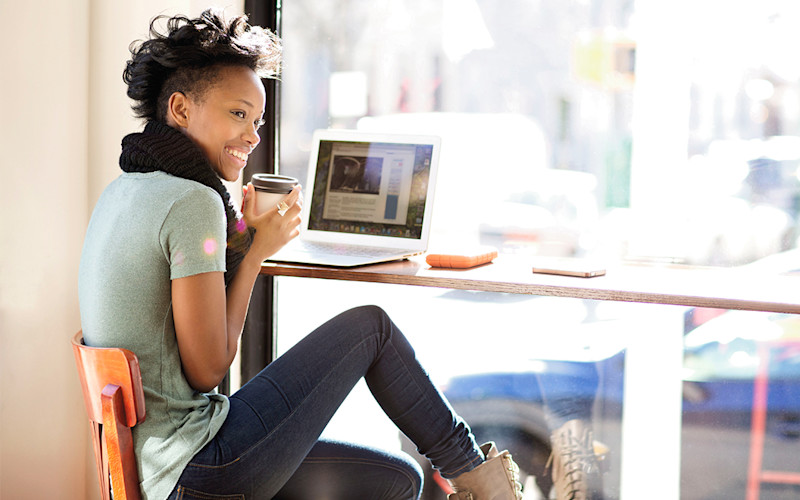 Female in coffee shop with laptop computer working and smiling