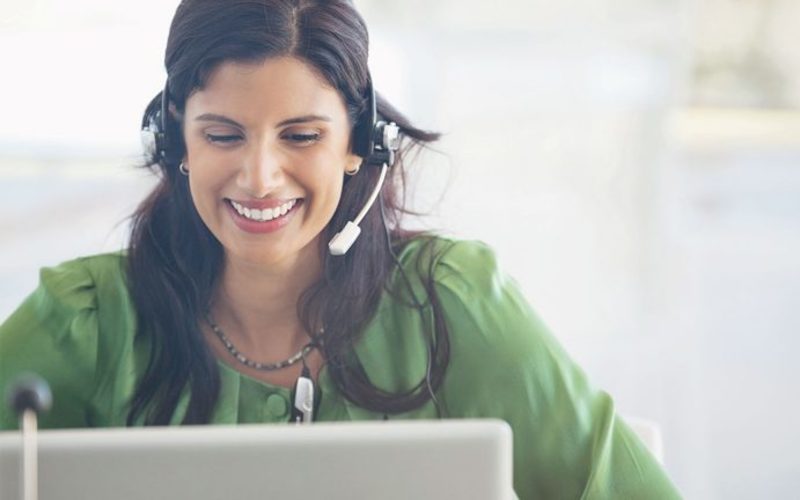 L female green top headset smiling laptop