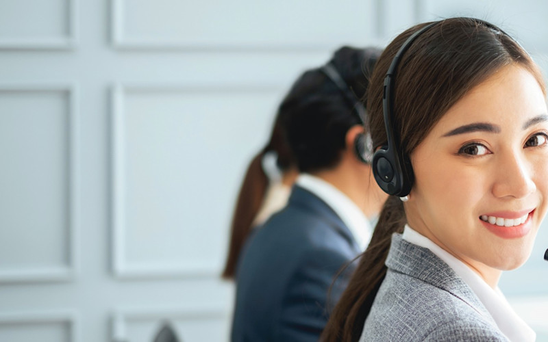 Call Center Rep with Headphones Smiling at the Camera