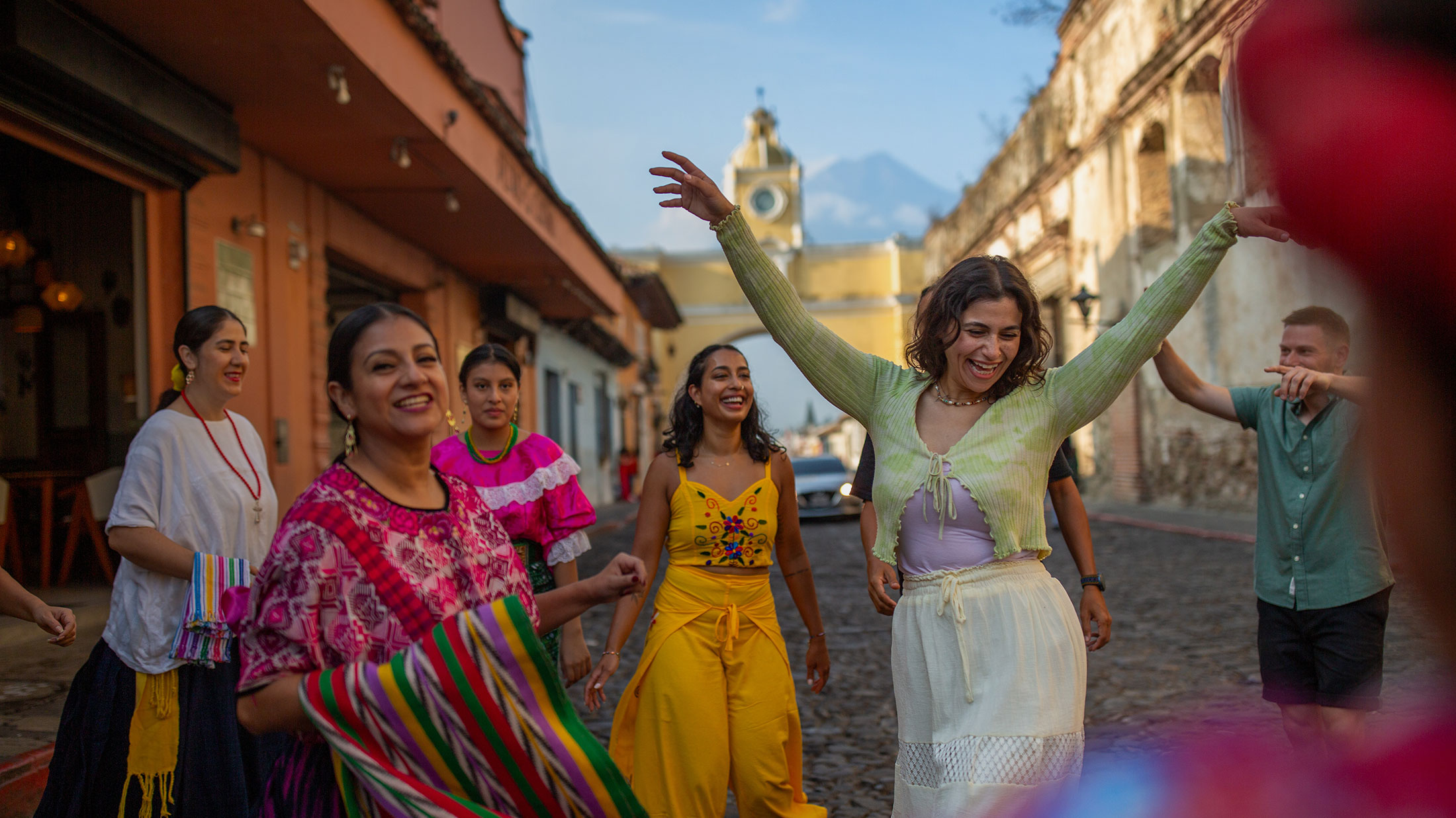 Travelers dance through the cobblestone streets of Antigua, Guatemala, with Santa Catalina Arch in the background Travelers dance through the cobblestone streets of Antigua, Guatemala, with Santa Catalina Arch in the background