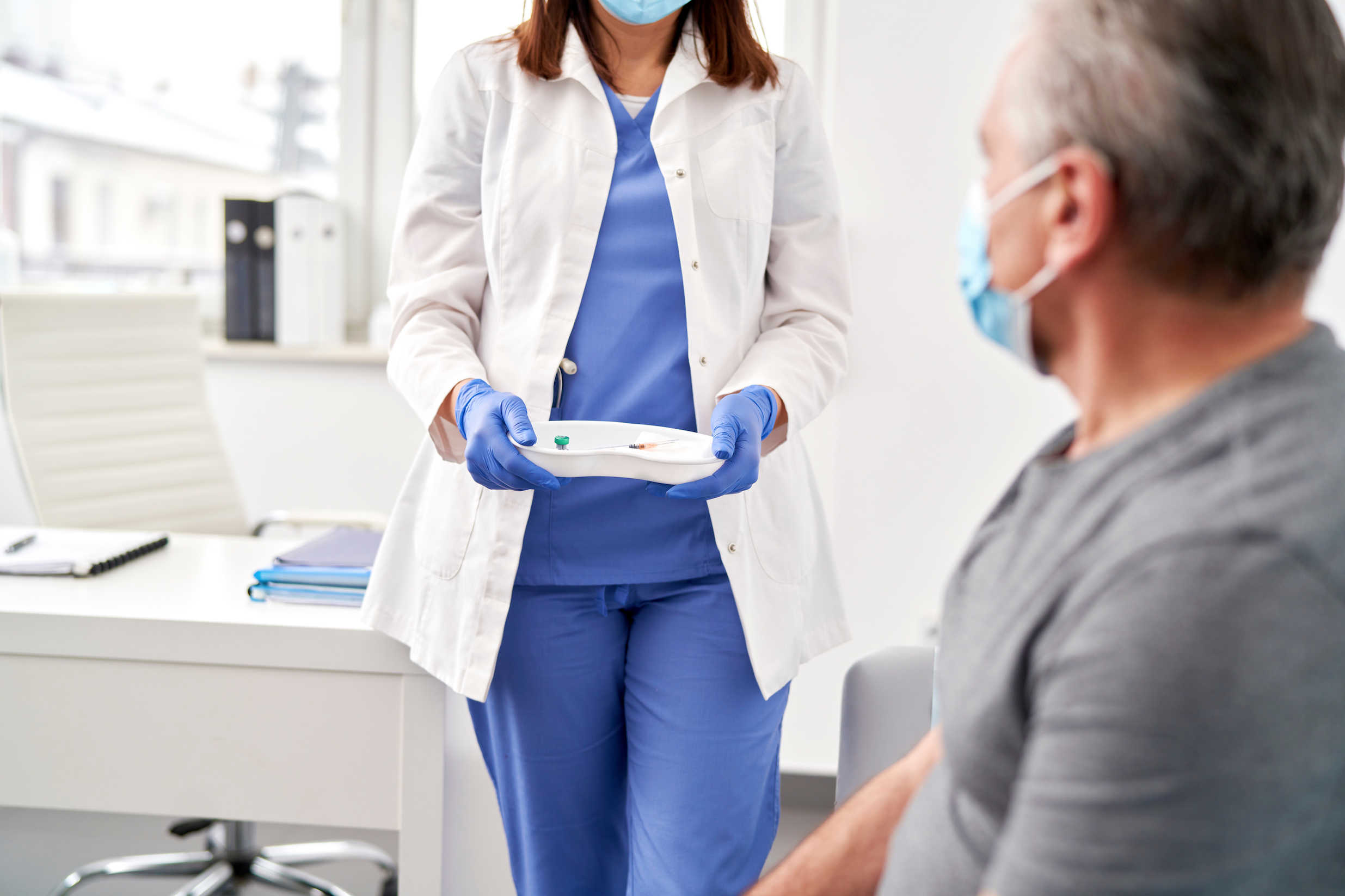 Doctor walking up to a patient with a mask on.