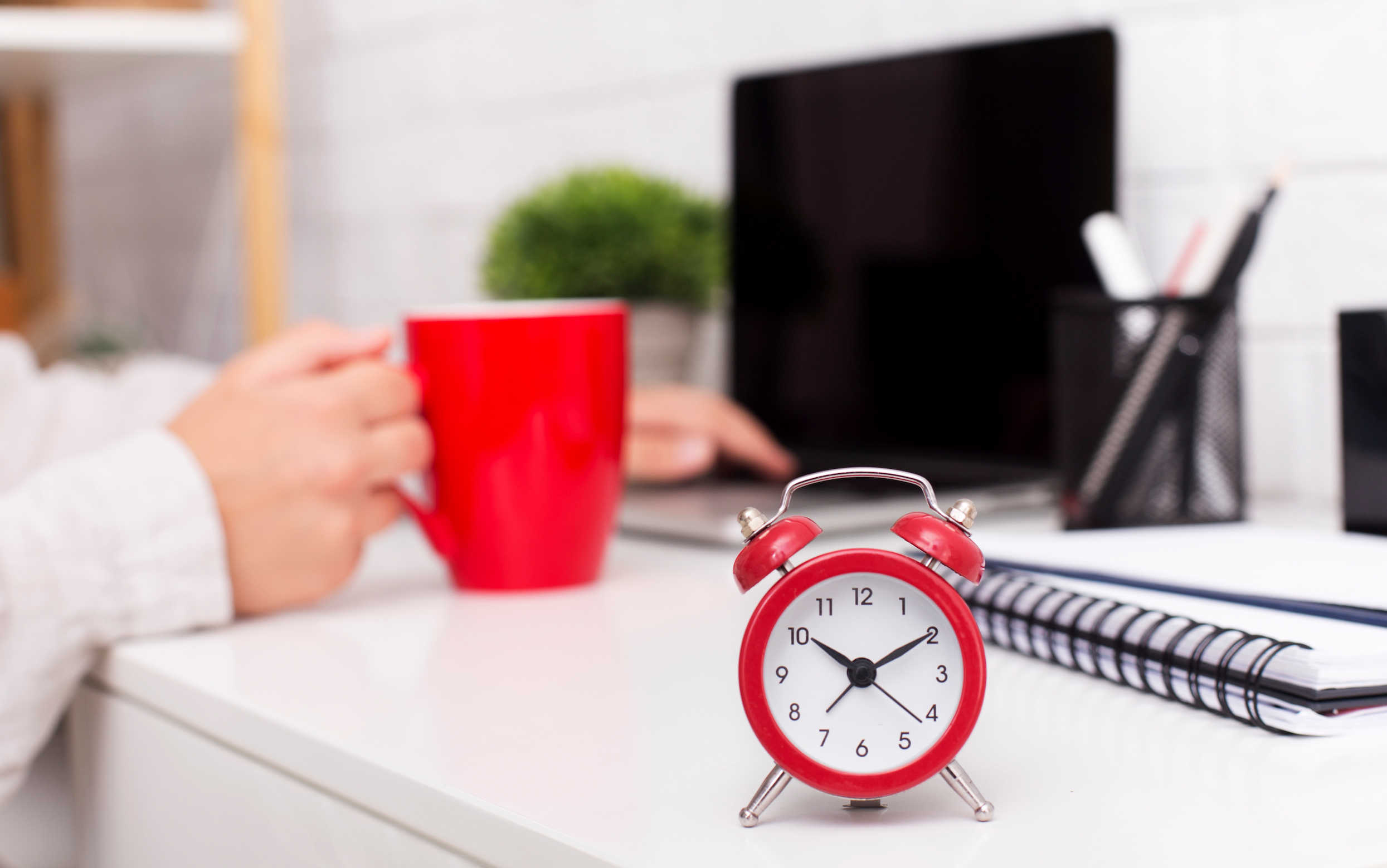 Time management concept. Red alarm clock and morning cup of coffee on office table, panorama