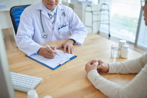 Doctor sitting down at a table across the way from a patient.