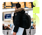 Traveler with a backpack looking at a flight arrival and departure board.