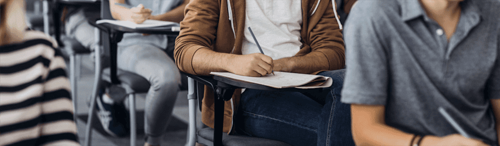 Students writing in notebooks at school desks