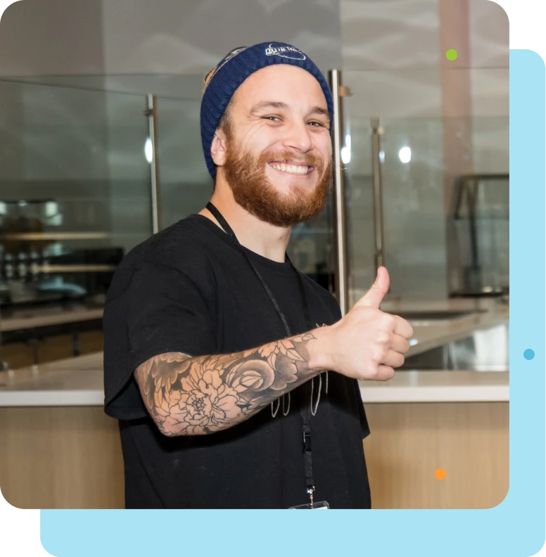 tattooed man with beanie giving thumbs up