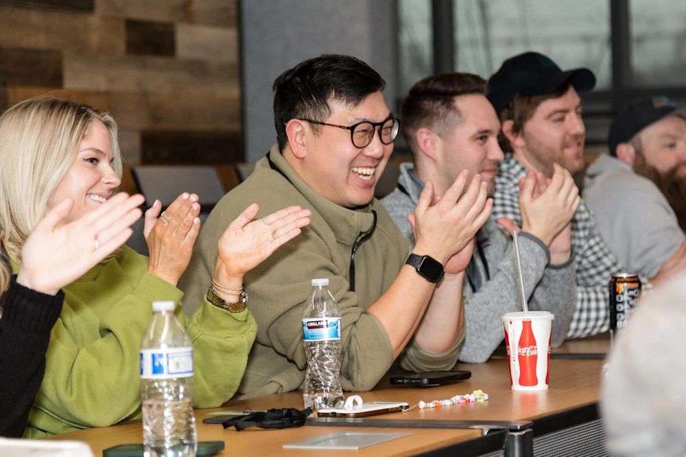 PDQ employees applaud a speaker presenting at the 2023 PDQ Week